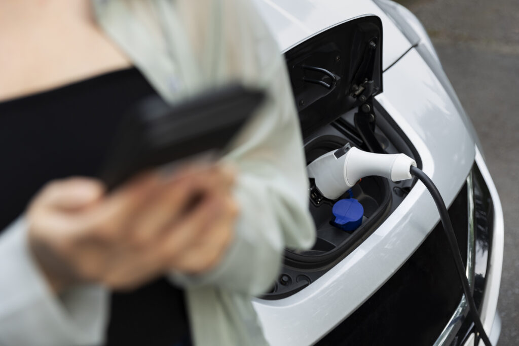 Woman Using Her Smartphone While Electric Car Is Charging