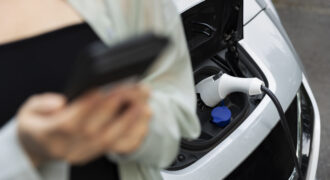 Woman Using Her Smartphone While Electric Car Is Charging
