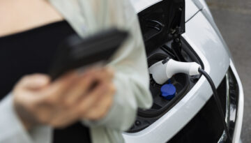 Woman Using Her Smartphone While Electric Car Is Charging