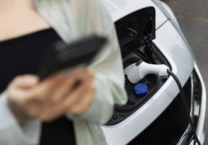 Woman Using Her Smartphone While Electric Car Is Charging