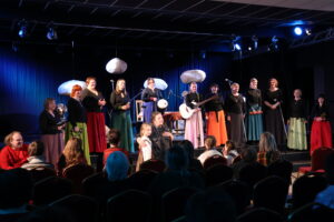 Stāstnieku festivāla Ziv zup koncertā Cik augšā sīku zvaigžņu, zemē sīku akmentiņu dalībnieki vienojas tautasdziesmā Upe nesa ozoliņu. Uz skatuves – Padures ansamblis Harmonija, centrā festivāla rīkotāja Ina Celitāne un mazā stāstniece Gerda Gruze.